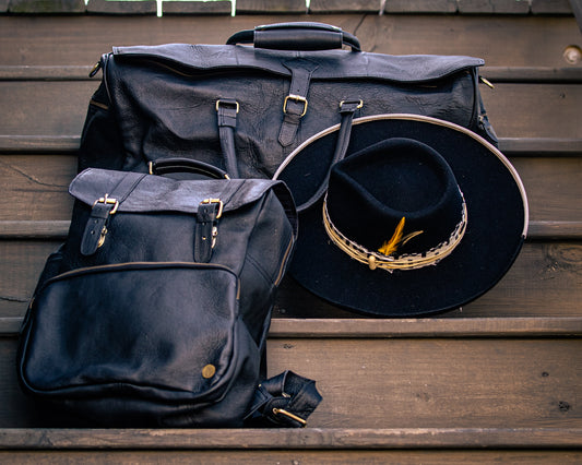 Black wide brim fedora with feather. Paired with leather backpack and leather duffel bag.